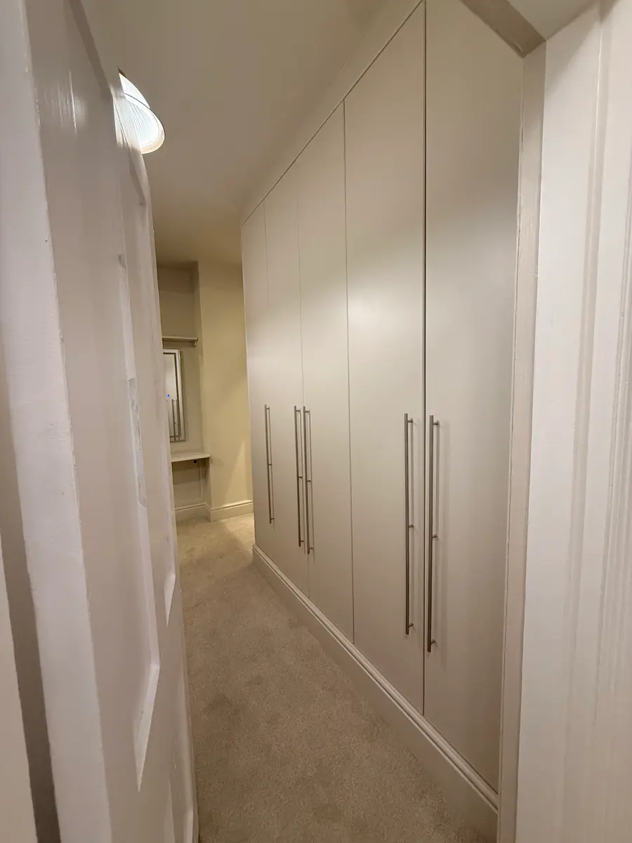 Run of floor-to-ceiling fitted wardrobes in white along a landing