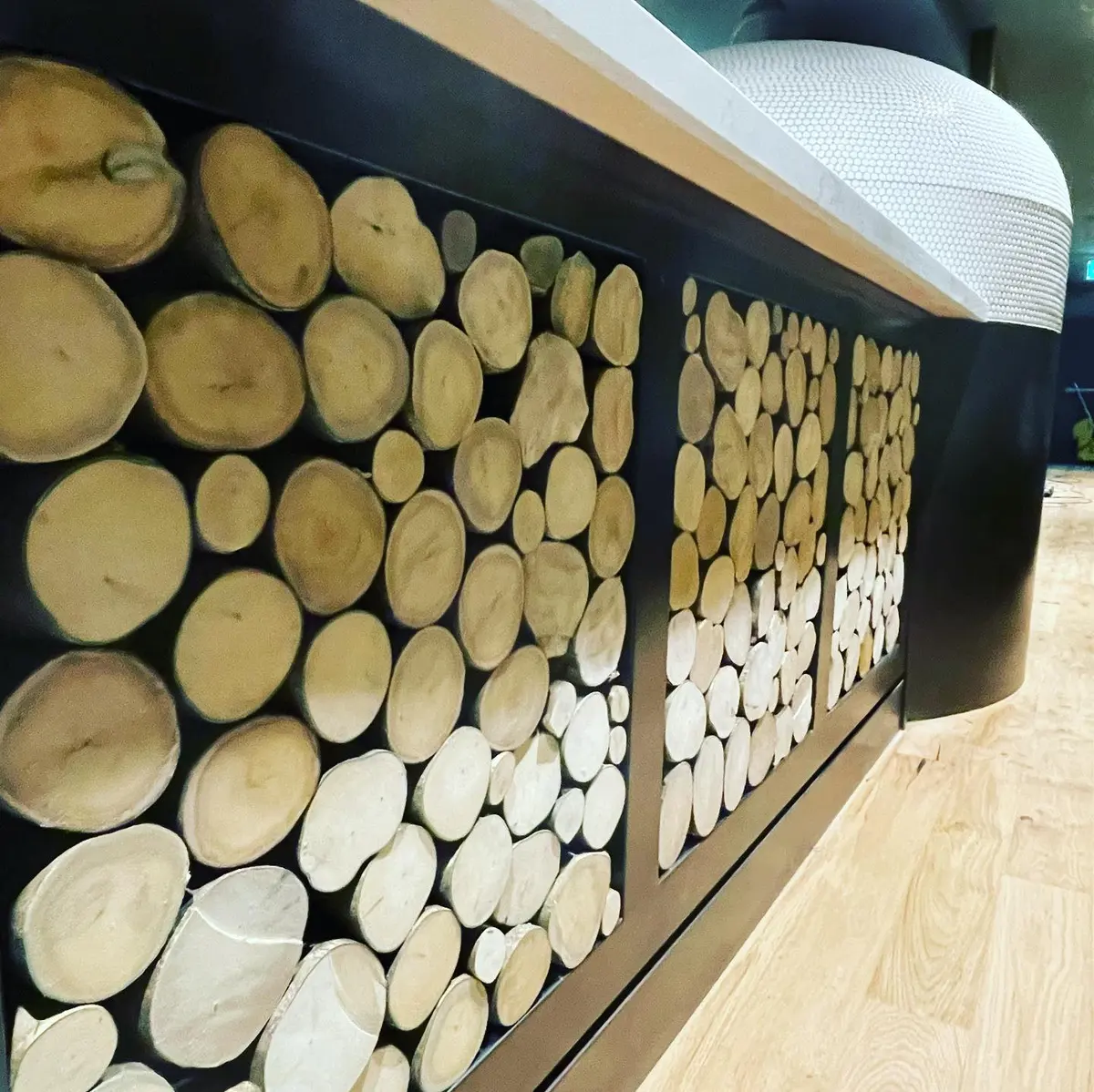 Curved counter faced with a timber log-slice feature wall