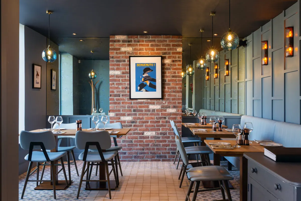Restaurant interior with panelled walls, exposed brick and pendant lighting
